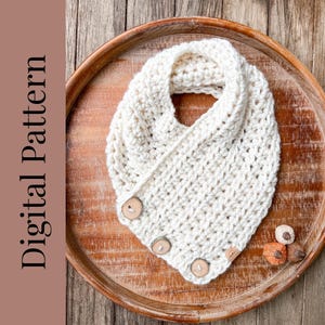 Puede incluir: Un cuello de punto de ganchillo blanco con tres botones de madera. El cuello se muestra en una bandeja de madera.