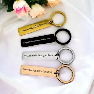 May include: Four keyrings with different coloured metal rings and engraved rectangular tags. The tags have the following text: "///diverting.flat.loving", "///expeditions.anathema.unwelcoming", "///offhand.clues.gambles", and "///producing.humid.exulted".