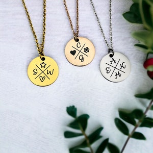 Può includere: Tre collane in oro, oro rosa e argento con ciondoli rotondi. Ogni ciondolo presenta un design a croce con iniziali e simboli, come un cuore, una stella e un fiore.