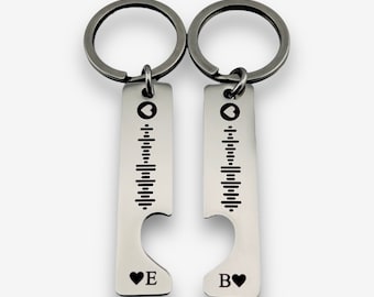 May include: A pair of silver keyrings with a heart-shaped cutout and a music note design. The keyrings are engraved with the letters "B" and "E" and a small heart.