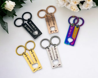 May include: Keychains in various metallic finishes, including black, gold, and iridescent, are displayed. Each keychain features a rectangular tag with a soundwave design and a heart-shaped cutout. Some keychains have initials and dates.