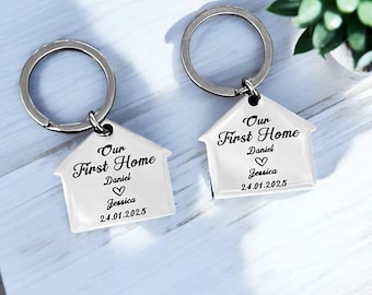 May include: Two silver house-shaped keychains with the text "Our First Home" and the names "Daniel" and "Jessica" with a heart symbol and the date "24.01.2025".
