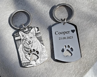 May include: Two silver dog tag keyrings. One has a detailed engraved image of a dog with a paw print cutout. The other tag has the name "Cooper", a heart, the date "25.08.2023", and a paw print.
