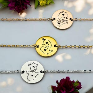 Könnte beinhalten: Drei Freundschaftsarmbänder mit goldenen, silbernen und roségoldenen Ketten. Jedes Armband hat einen runden Anhänger mit einer Umrandung von zwei Bundesstaaten, die durch ein Herz verbunden sind. Die Anhänger sind mit den Bundesstaaten Kanada und den Vereinigten Staaten graviert.