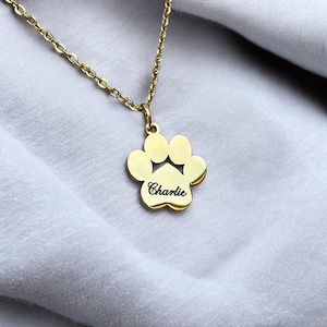May include: Gold paw print necklace with the name "Charlie" engraved on it.