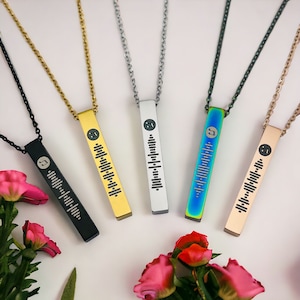 May include: Five bar necklaces with different coloured metal finishes. Each necklace features a musical note and a barcode-like design. The necklaces are displayed against a white background.