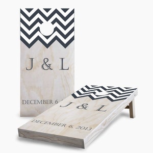 May include: A wooden cornhole game with a black and white chevron pattern. The game is personalized with the initials "J & L" and the date "December 6, 2013".