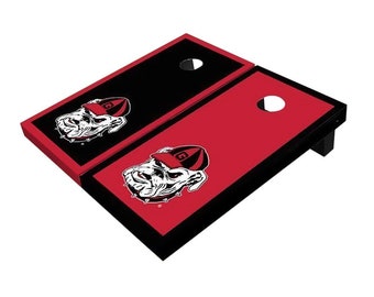 May include: A red and black regulation size cornhole set with a University of Georgia Bulldogs logo. The logo features a bulldog wearing a red and black hat.
