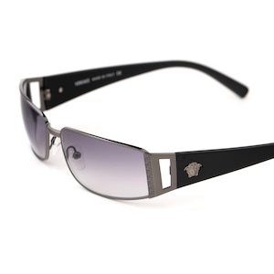 May include: Black and silver-toned sunglasses with a rectangular frame and gradient lenses. The sunglasses feature a decorative Greek key design on the temples and a Medusa head emblem. The arms are black.