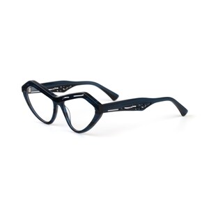 May include: Dark blue eyeglasses with a distinct geometric, angular frame shape. The temples feature a decorative cutout pattern along the sides. These glasses have clear lenses and a glossy finish, showcasing a bold, structured design throughout.
