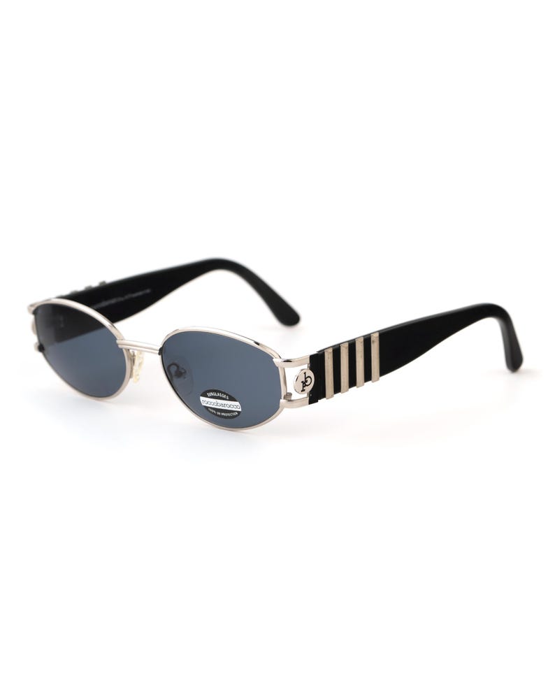May include: Oval-shaped sunglasses with a silver frame and dark lenses. The temples are black with silver vertical stripes. The sunglasses have a classic, retro design.