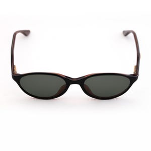 May include: Black oval sunglasses with dark lenses. The frames are black with brown accents and temples. The sunglasses are set against a white background.
