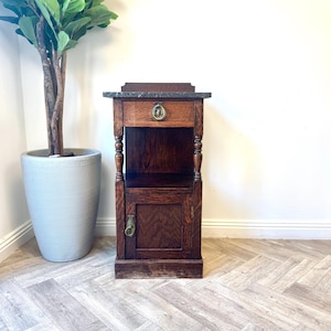 May include: A dark wood bedside table with a single drawer and a cabinet door. The table has a marble top and brass hardware.
