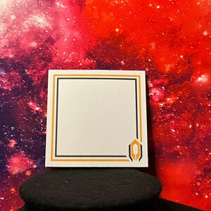 Könnte beinhalten: Ein weißer quadratischer Aufkleber mit einem schwarzen und orangefarbenen Rand und einem geometrischen Design in der unteren rechten Ecke. Der Aufkleber befindet sich vor einem lebendigen roten und lila Galaxiehintergrund.