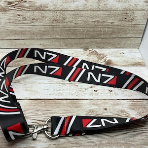 May include: Black and red lanyard with the text "N7" repeated across the strap. The lanyard has a silver metal clip.