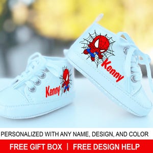 May include: White canvas high-top baby shoes with a red and blue Spiderman design and the name "Kenny" embroidered on the side.