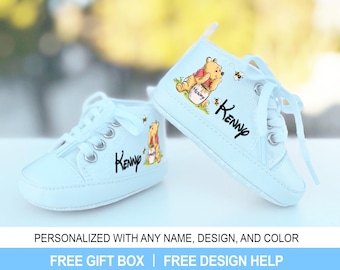 Könnte beinhalten: Ein Paar hellblaue Babyschuhe mit einem Winnie Puuh-Motiv. Die Schuhe haben einen weißen Schnürverschluss und der Name "Kenny" ist darauf geschrieben.