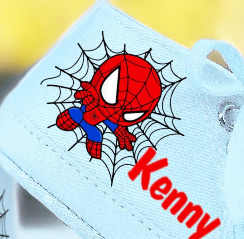 May include: Light blue canvas shoes with a cartoon image of Spiderman in a web. The name "Kenny" is written in red letters on the shoe.