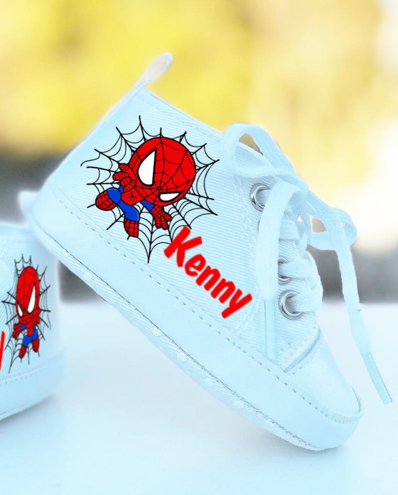 May include: White canvas baby shoes with a red and blue Spiderman design and the name "Kenny" written in red letters.