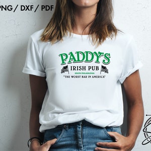 May include: A white t-shirt with a green and black graphic design that reads "Paddy's Irish Pub South Philadelphia "The Worst Bar in America".