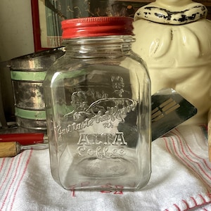 Vintage Alta Coffee  jar.  Vintage clear glass Alta Coffee jar with red metal lid, embossed lettering on 2 sides.