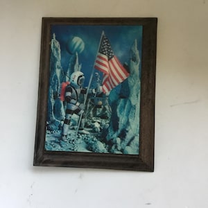 Small plastic based lenticular 3D picture of NASA astronaut planting of USA flag on the moon. Lenticular moon landing/flag planting hanging.