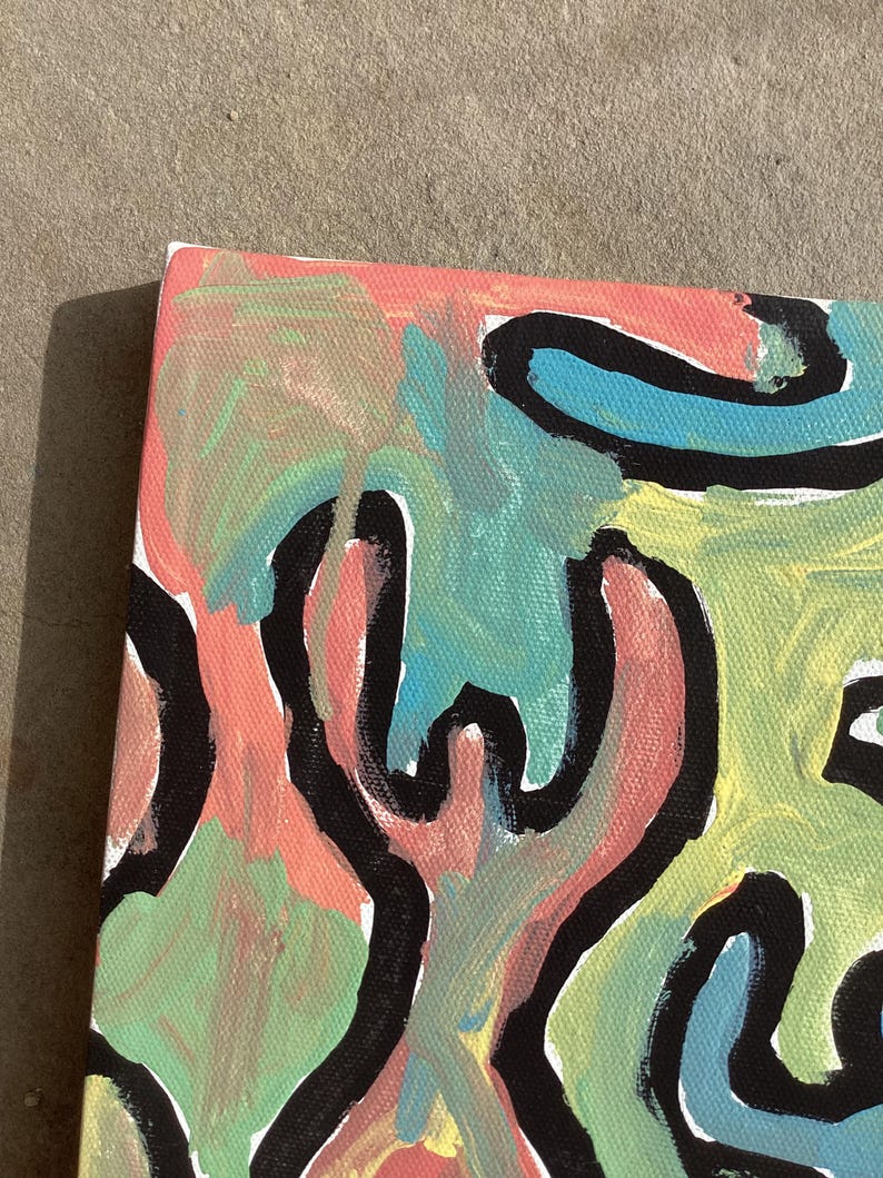 Puede incluir: Pintura abstracta sobre lienzo con superficie texturizada. La obra presenta una vibrante mezcla de colores, incluyendo coral, azul claro y verde, con contornos negros audaces. La composici&oacute;n es una vista de cerca de la esquina del lienzo.