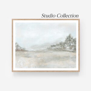 Peut inclure: Peinture de paysage encadrée aux couleurs neutres. L'œuvre présente une représentation floue d'un champ et d'arbres sous un ciel brumeux. Le texte "Studio Collection" est visible en haut.