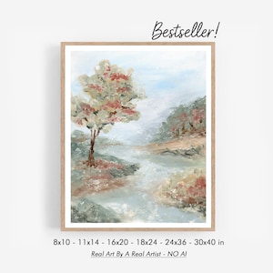 Puede incluir: Pintura de paisaje enmarcada con un marco de madera clara. La obra representa una serena escena fluvial con un árbol y follaje en tonos apagados de verde, beige y rojo. El texto "Bestseller!" está en la esquina superior derecha. Tamaños disponibles: 20,3x25,4cm a 76,2x101,6cm.