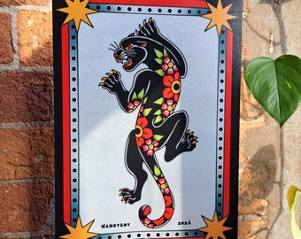 May include: A black panther with red and yellow flowers printed on its body. The panther is standing on its hind legs with its front paws raised. The image is framed with a black border and gold stars in the corners. The text "NANCYBOY 2023" is printed at the bottom of the image.