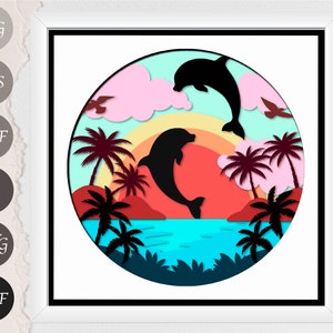 May include: A framed, layered paper art piece featuring a tropical sunset scene. Two black dolphins leap and swim in front of a red and orange sunset, with palm trees and birds. The background is a gradient of blue, pink, and yellow.