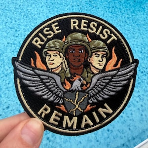 May include: Embroidered patch with the words "RISE RESIST REMAIN" in gold lettering on a black background. The patch features three figures in military helmets, flames, and a silver eagle with outstretched wings. A unique patch.