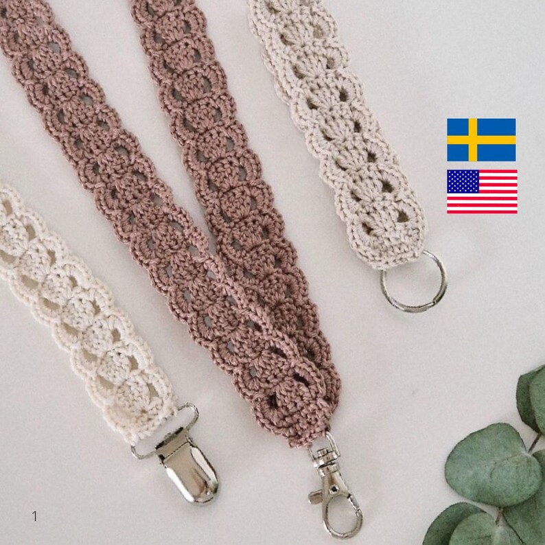 Op de afbeelding: Close-up van drie gehaakte lanyards in cr&egrave;me, mauve en beige. Elke lanyard heeft een decoratief openwerkpatroon en is afgewerkt met een metalen sluiting of ring. De lanyards worden getoond tegen een lichte achtergrond.