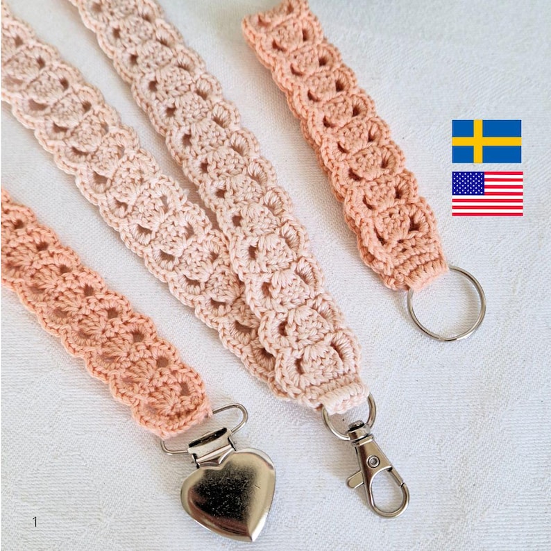 Op de afbeelding: Vier handgemaakte gehaakte lanyards in perzik- en cr&egrave;metinten. De lanyards hebben een herhalend opengewerkt patroon en zijn afgewerkt met metalen hardware, waaronder een hartvormige clip, een draaibare sluiting en een splitring. De lanyards worden op een wit oppervlak gepresenteerd.