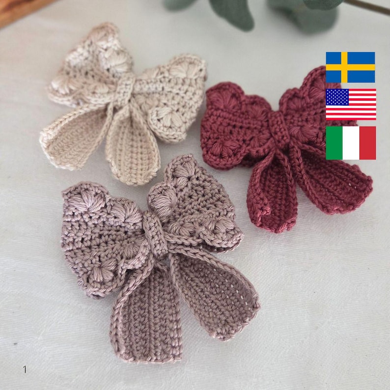 May include: Three handmade crochet bows in shades of beige, mauve, and burgundy. The bows have a textured, floral-like pattern on the center and the loops. The bows are arranged on a light-colored surface, showcasing their delicate craftsmanship.