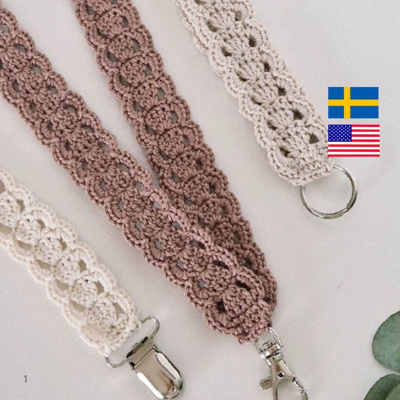 Op de afbeelding: Close-up van drie gehaakte lanyards in cr&egrave;me, mauve en beige. Elke lanyard heeft een decoratief openwerkpatroon en is afgewerkt met een metalen sluiting of ring. De lanyards worden gepresenteerd tegen een zachte, neutrale achtergrond.