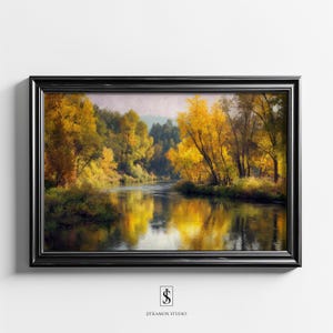Puede incluir: Una pintura de paisaje enmarcada representa una escena de río con árboles en colores otoñales. La obra de arte presenta un marco negro y una vista serena de un río que refleja el follaje dorado. La pintura es de Jitkamon Studio.