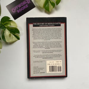 K&ouml;nnte beinhalten: Ein Taschenbuch mit dem Titel "The History of Middle-earth" von Christopher Tolkien. Das Buch hat einen schwarzen Einband mit rotem und wei&szlig;em Text. Das Buch ist von gr&uuml;nen Bl&auml;ttern und einem lila Aufkleber mit der Aufschrift "OFFWORLD BOOKS" umgeben.