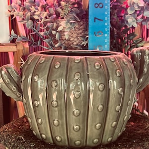 Pu&ograve; includere: Una tazza di ceramica bianca con un manico nero e la scritta "But First, Coffee" in nero, con un carattere a mano. La tazza &egrave; su una superficie bianca.