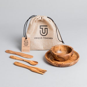 May include: A set of olive wood serving bowls and utensils, including a small bowl, a larger serving plate, a butter knife, a spoon, and a fork. The set is packaged in a burlap bag with the logo "UNIQUE-TOUCHES" printed on it.