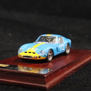 Puede incluir: Modelo en miniatura de un coche de carreras azul y amarillo con el número 112, expuesto sobre una base de madera. El coche tiene una franja amarilla y una parte delantera amarilla. Es un artículo de colección.