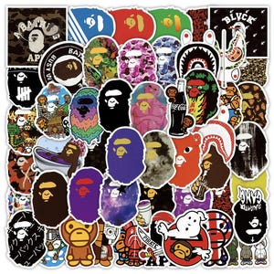 May include: A collection of colorful stickers featuring various designs, including ape faces, shark faces, and other graphic elements. The stickers are in various shapes and sizes, with a mix of bold colors and patterns.