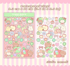 May include: Two sheets of waterproof vinyl stickers with bear and bunny characters, apples, and other shapes. The stickers measure 9.3 cm x 14 cm. The text "Trinket Galore" and "studio memoli" are visible on the sheets.