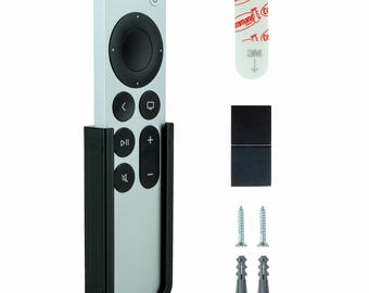 Może przedstawiać: Czarny uchwyt ścienny do pilota Apple TV. Uchwyt ma szczelinę na pilota i małą taśmę samoprzylepną do montażu. Uchwyt jest pokazany z wkrętami i kołkami do montażu.