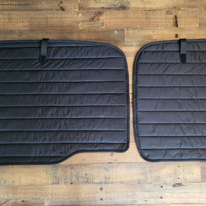 May include: Two black quilted window shades with a hook and loop fastener. The shades are designed to block out light and heat.