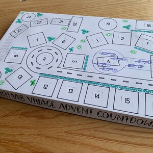 K&ouml;nnte beinhalten: Eine wei&szlig;e Weihnachtsdorf-Adventskalender-Box mit einem handgezeichneten Dorfdesign. Das Design umfasst nummerierte K&auml;stchen, Stra&szlig;en und dekorative Elemente. Der Text "CHRISTMAS VILLAGE ADVENT COUNTDOWN" ist sichtbar.