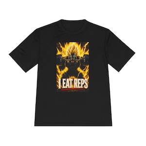 以下が含まれることがあります： 黒の半袖Tシャツ。スパイクヘアの筋肉質な人物が黄色い稲妻に囲まれながらバーベルを持ち上げているグラフィックがプリントされています。人物の下には、太字の明るいフォントで「I EAT REPS」というテキストが印刷されています。