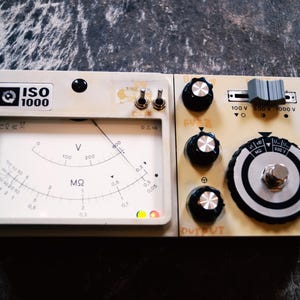 May include: Vintage beige electronic testing device with dials, knobs, and a meter labeled "ISO 1000". The meter displays voltage (V) and megaohms (MΩ). Features include a switch for voltage selection and a large dial with a central button.