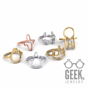 May include: Collection of seven open-design rings in gold, silver, and rose gold tones. The rings feature various geometric and abstract shapes. The Geek Jewelry logo is visible in the bottom right corner.