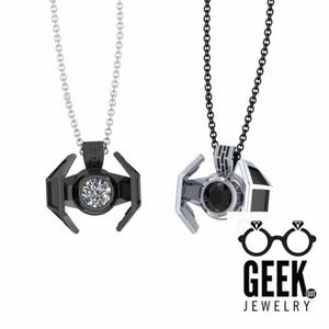 May include: Two pendant necklaces featuring a TIE fighter design. One is black with a clear stone, the other is silver with a black stone. Both hang from chain necklaces. The Geek Jewelry logo is in the bottom right.